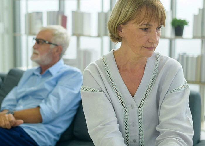 Middle-aged woman and man sitting apart indoors, reflecting on the real benefits for women to get married.