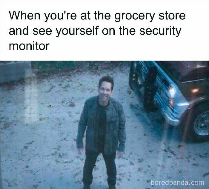 Man smiling and looking up at security monitor outside, depicting a relatable specific moment in life experience.