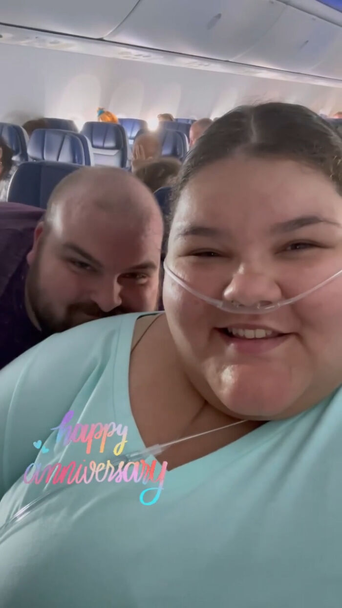 Plus-size activist smiling on a plane with oxygen tube, celebrating anniversary during a flight with a male companion. Plus-size activist smiling on a plane with oxygen tube, celebrating anniversary during a flight with a male companion.