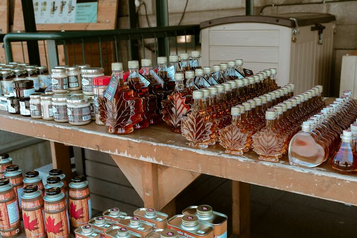 Bottles of maple syrup and jars on display at a market, showing foods not popular in their country despite tourist appeal.