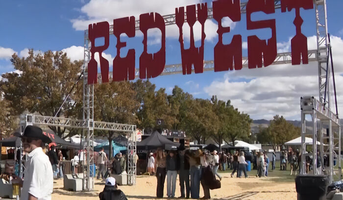 Crowd gathers under Red West music festival sign where a woman tragically lost her life in a freak accident.