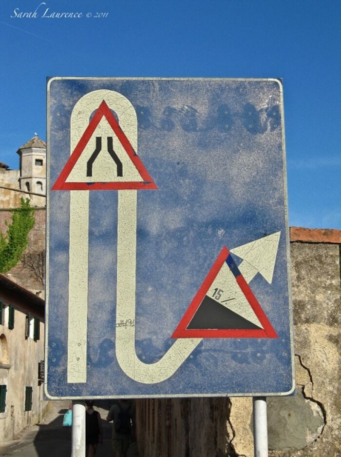 Confusing road sign showing a narrowing road and steep incline with unclear direction, illustrating confusing road signs.