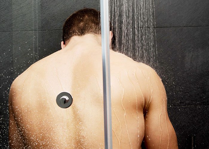 Man with muscular back taking a shower, reflecting on childhood cringe moments including making cat noises as kids.