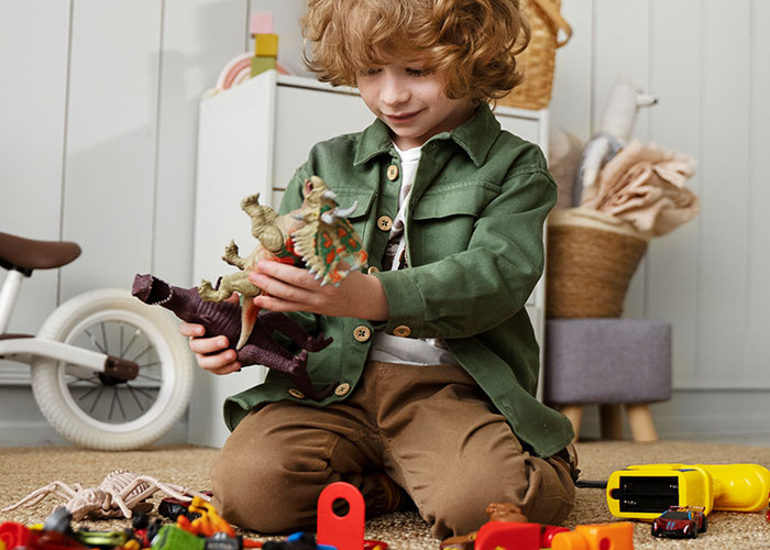Young child playing with dinosaur toys, recalling childhood memories that make people cringe to this day.