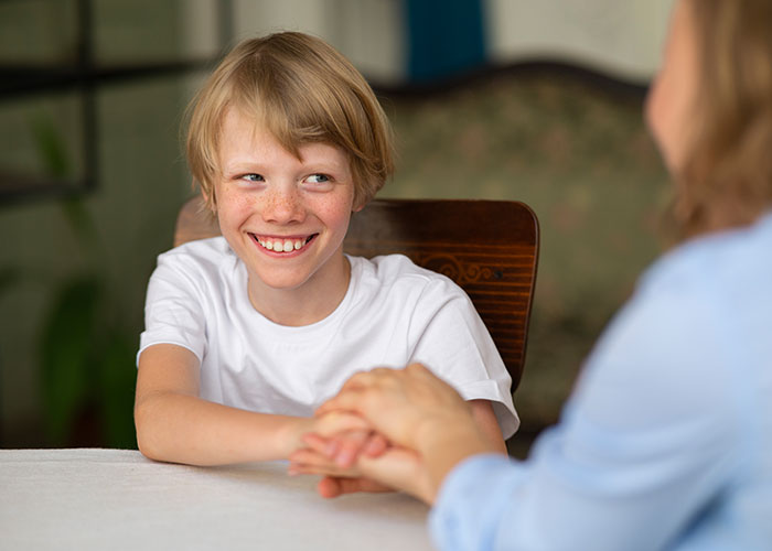 Smiling child with freckles holding hands with adult, reflecting on childhood moments that make them cringe today.