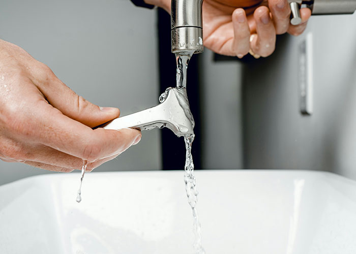 Hands holding a dental tool under running water in a clinical setting during a facepalm-worthy doctor’s visit.