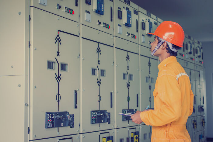 Electrician wearing orange safety gear inspecting electrical panels, showing moments the universe protected people from harm.