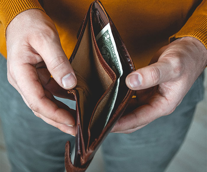 Man holding open brown wallet with a single dollar bill inside, symbolizing theft and refusal to forgive ex-friend.