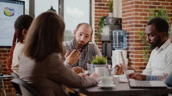 Man discussing trust issues in a business meeting, refusing to forgive ex-friend accused of theft years ago.