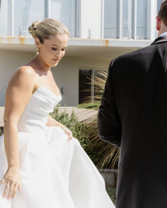 Bride in white wedding dress with groom in black suit during outdoor wedding photo session with professional photographer.