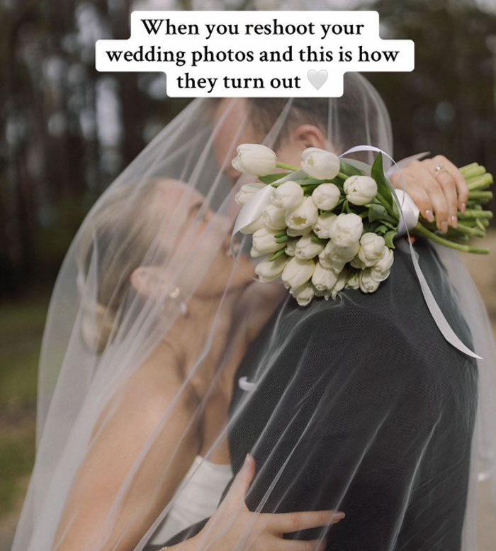 Bride and groom under a veil holding white tulip bouquet during outdoor wedding photoshoot.