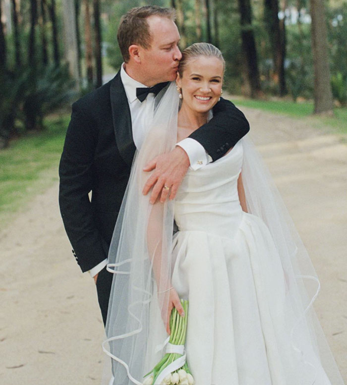 Bride and groom posing outdoors on wedding day, showcasing moments captured by well-known professional photographer.