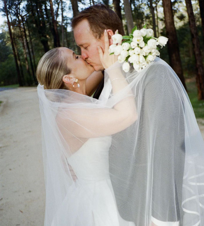 Bride and groom kissing outdoors, wedding ceremony with bouquet and veil in a forest setting, wedding pics photo session.
