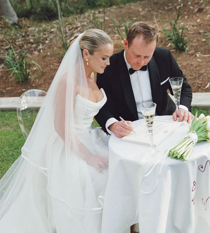 Bride and groom at wedding signing documents outdoors, a well-known professional hired for wedding pics.