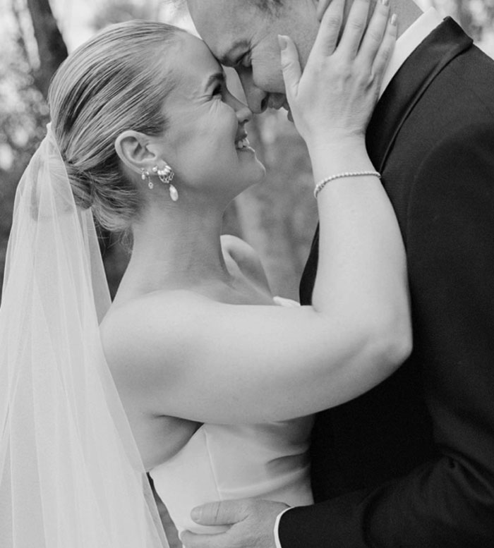 Bride and groom embracing closely during wedding photoshoot by a well-known professional photographer outdoors.