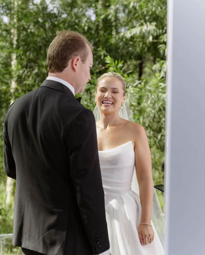 Bride and groom at outdoor wedding ceremony, bride smiling, captured by well-known professional wedding photographer.