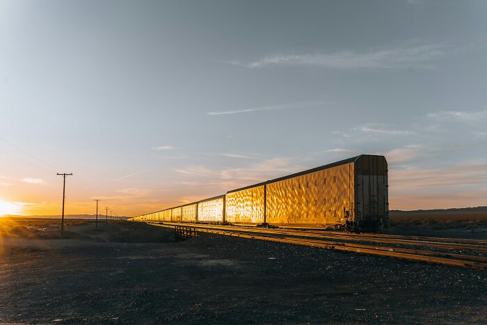 Long train cars reflecting sunlight on tracks in a wide open landscape, illustrating unbelievable facts about countries.