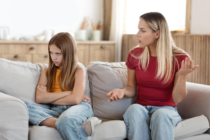 Mother and daughter in a tense moment on couch, highlighting family scapegoat regret and emotional conflict.