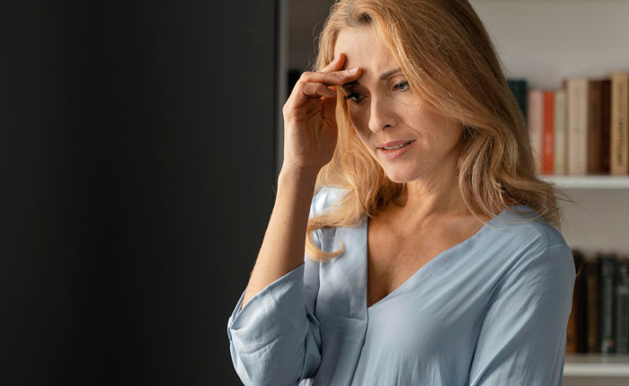 Worried mother reflecting in a room, expressing regret about using daughter as a family scapegoat years later.