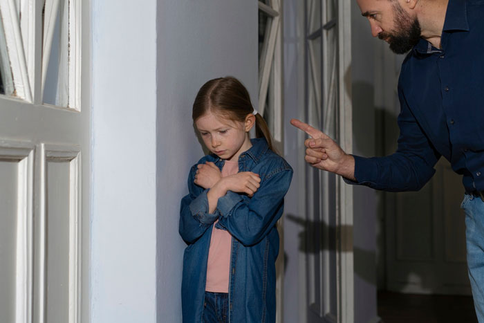 Young daughter looking upset while being scolded, highlighting family scapegoat and regret themes.