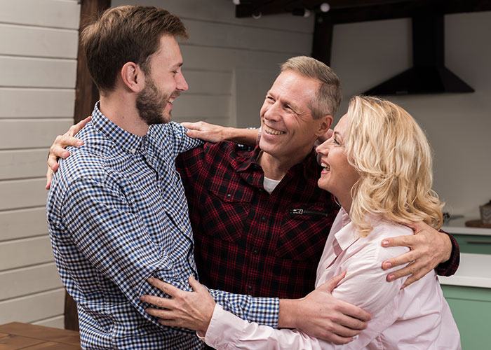 Three family members warmly embracing and smiling, preparing for a separate drive to Disneyland together.