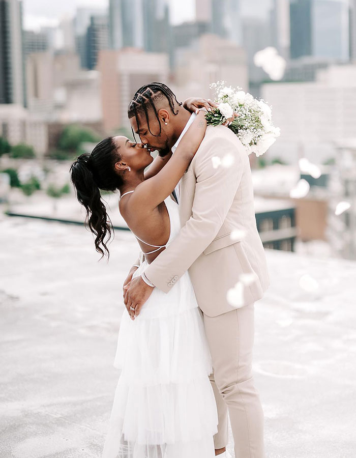 Simone Biles and Jonathan Owens sharing an intimate moment with city skyline in the background.