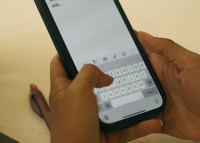 Hands holding a smartphone typing on the touchscreen keyboard.