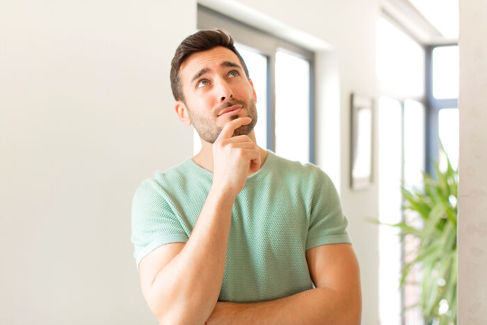 Thoughtful man in a green shirt looking up, representing curiosity about mysteries that once baffled the world now solved.