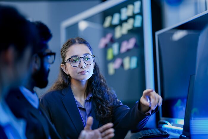 Two professionals discussing work at a computer, illustrating people who lost their jobs to AI in tech environment.