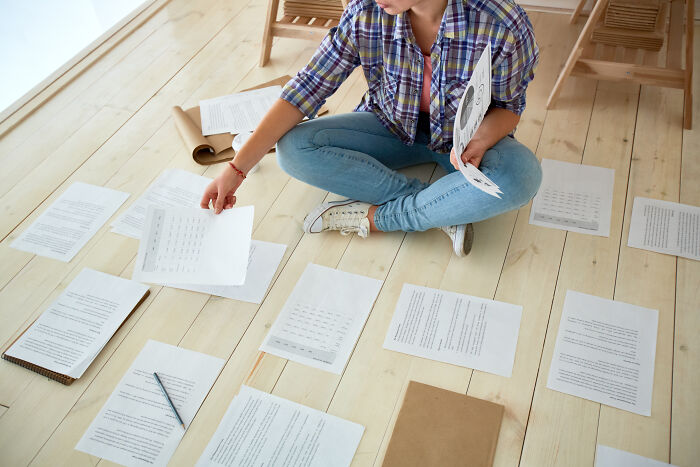 Person sitting on wooden floor sorting through scattered papers and documents about unexplainable creepy things experienced.