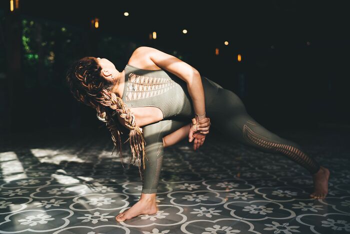 Woman in athletic wear performing a deep stretch on patterned floor, demonstrating simple car stuff skills with focus and balance.
