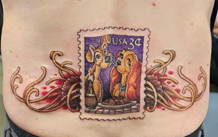 Colorful tattoo of a USA 3-cent stamp featuring cartoon dogs with pasta on a person's lower back by tattoo artists refused to ink.