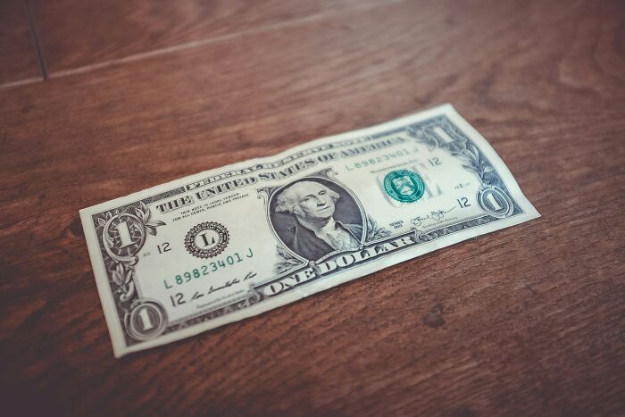 One dollar bill on wooden surface symbolizing tips to outsmart burglars and protect your home effectively.