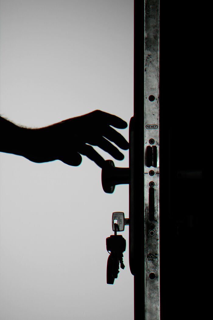 Silhouette of hand reaching for door handle with keys, illustrating how to outsmart burglars and protect your home.