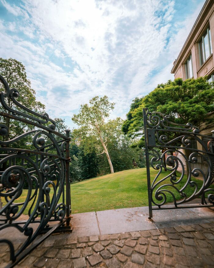Ornate iron gates open to a lush home garden, highlighting ways to outsmart burglars and protect your property.