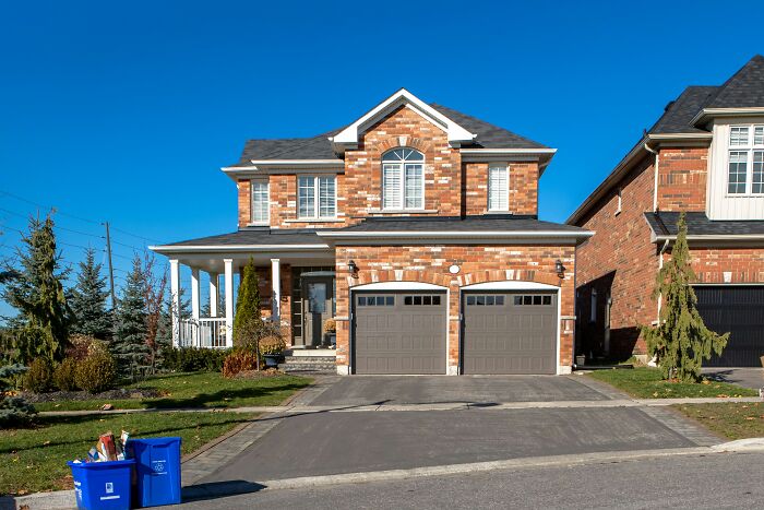 Brick suburban house with double garage on a clear day showcasing home security to outsmart burglars and protect the home.