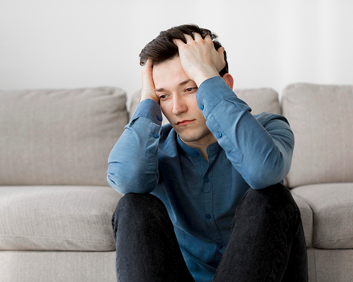 Young man sitting on floor holding head in hands, appearing stressed and reflecting on bio mom abandoning him years ago. Young man sitting on floor holding head in hands, appearing stressed and reflecting on bio mom abandoning him years ago.