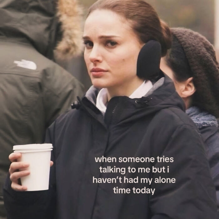 Woman in winter coat holding coffee with a relatable meme about anxiety and needing alone time for coping.