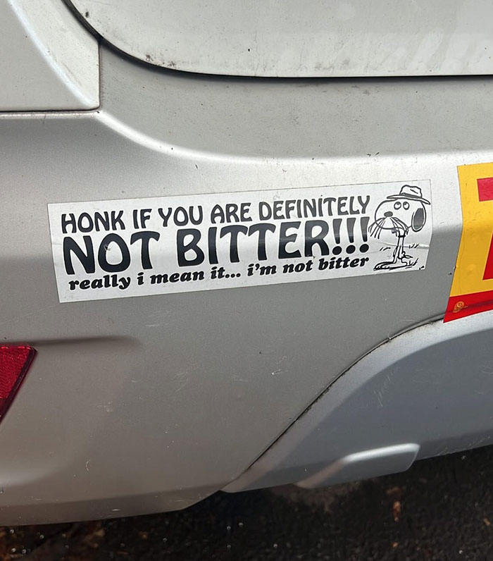 Funny bumper sticker on a silver car saying honk if you are definitely not bitter with a cartoon dog drawing.