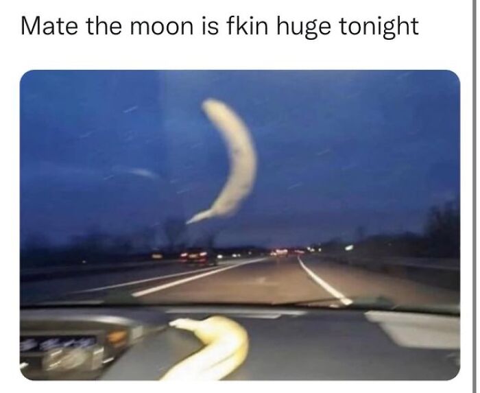 Banana shaped like a crescent moon, viewed from a car dashboard, creating a humorous meme for laughter and fun.