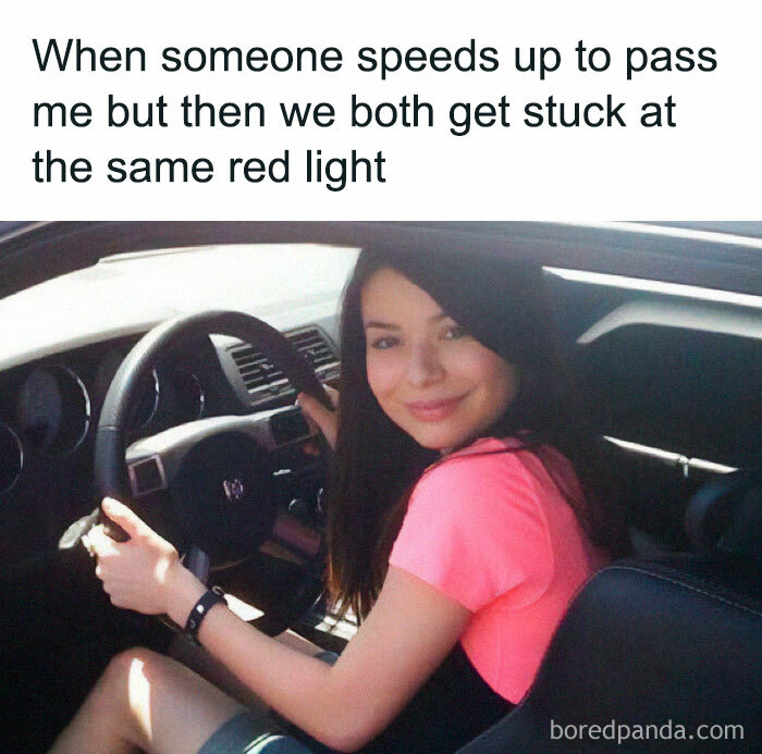 Woman smiling behind the wheel, illustrating a driving meme about road rage and being stuck at the same red light.