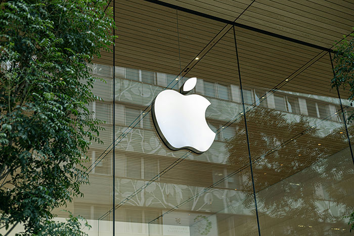 Apple store logo on glass wall with tree reflections, illustrating older people clueless with technology moments online