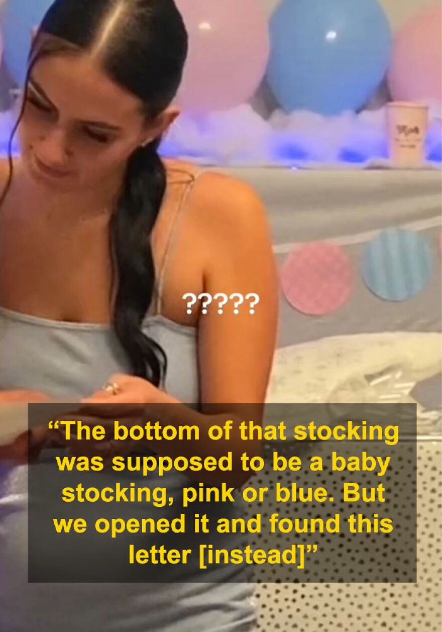 Woman at gender reveal party looking down, with pink and blue balloons and decorations in the background.