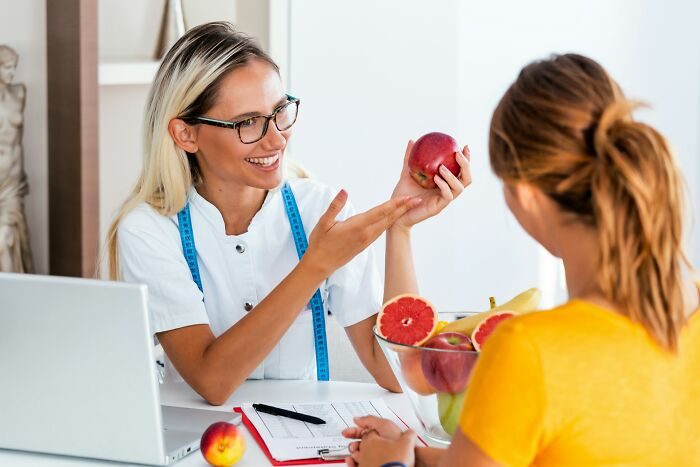 Doctor explaining healthy eating with fruits to patient during consultation about strange health hacks.