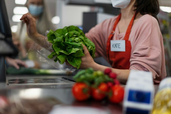 Grocery cashier holding lettuce with tomatoes and a milk carton nearby, illustrating moments of misreading social cues.