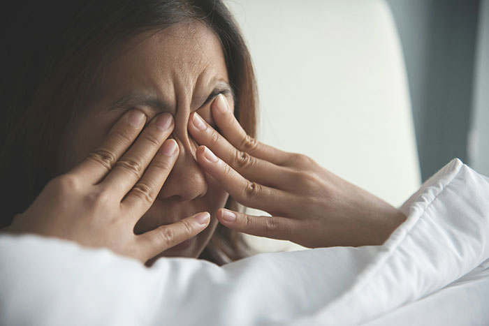 Stressed woman covering her eyes in bed, reflecting the emotional strain of a financial favor and loan repayment situation. Stressed woman covering her eyes in bed, reflecting the emotional strain of a financial favor and loan repayment situation.