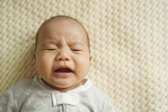 Crying baby lying on a textured surface, illustrating emotional moments related to near-death experiences topics.