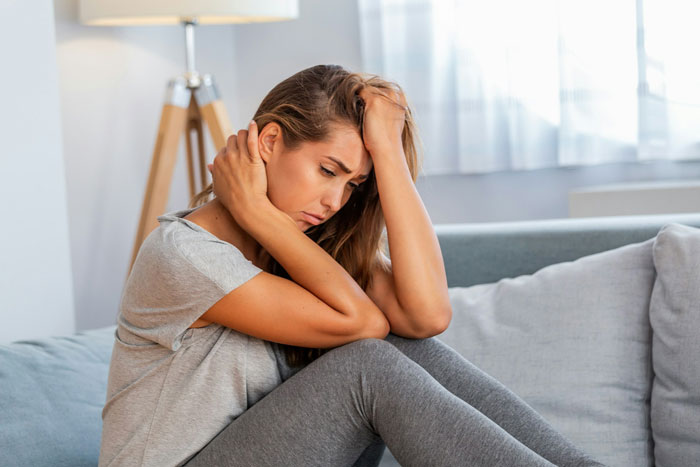 Woman sitting on couch looking distressed after learning about man she&rsquo;s been seeing getting married soon.