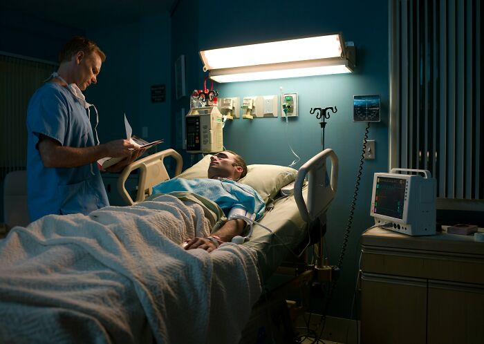Nurse checking a patient in a dimly lit hospital room, setting a scene for scary ghost stories in hospital work.