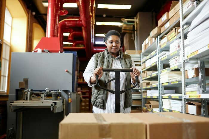 Person handling cardboard boxes in a warehouse.